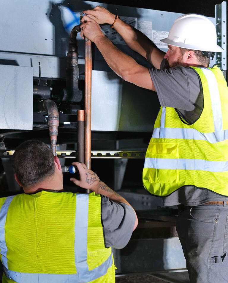 commercial hvac & refrigeration technicians work on a unit.