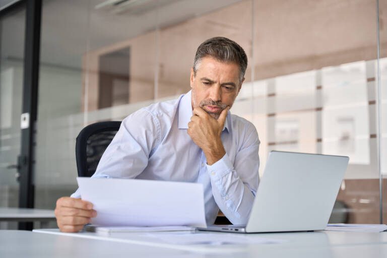 Businessman studying documents related to downtime and its impact on operations.