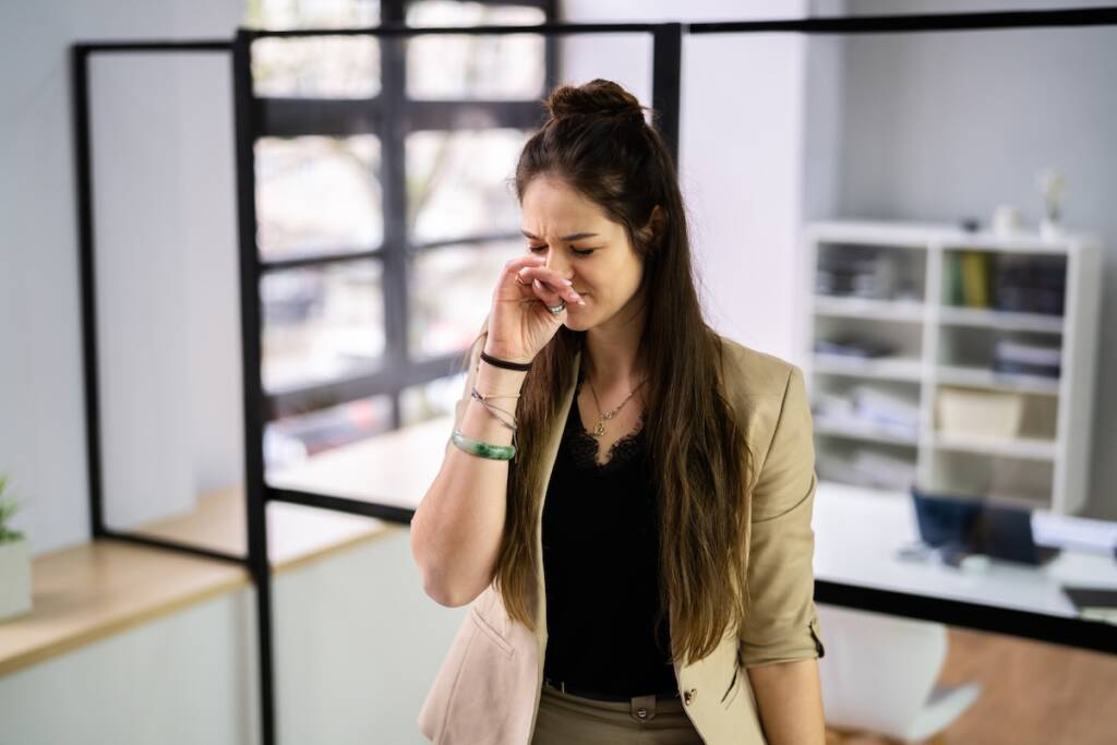 Woman reacting to bad odors inside a building, a common sign you may need commercial AC repair Dallas services.