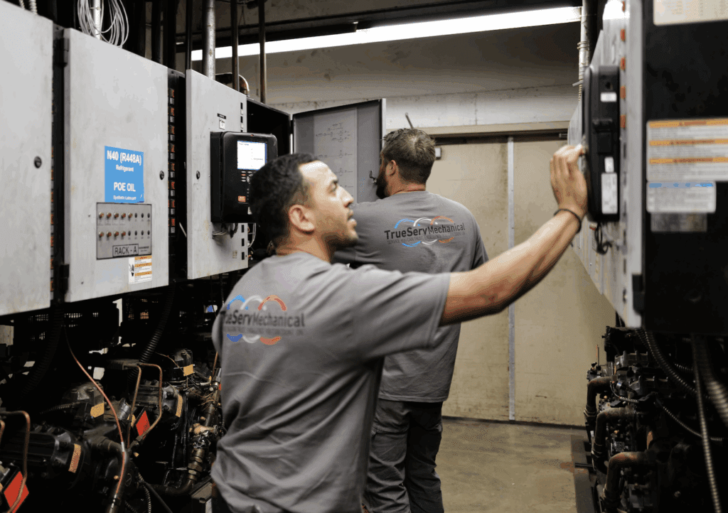 Two TrueServ Mechanical technicians working together on commercial HVAC equipment