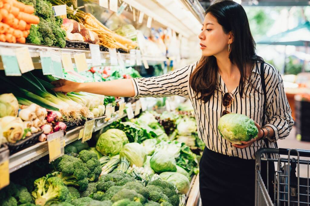 Woman choosing produce in a grocery store refrigeration aisle